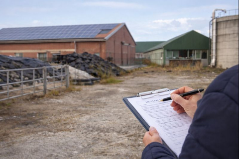 Boerderij met man die op clipboard schrijft